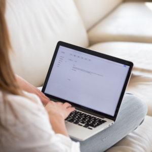 Rear view at woman writing email on laptop at home