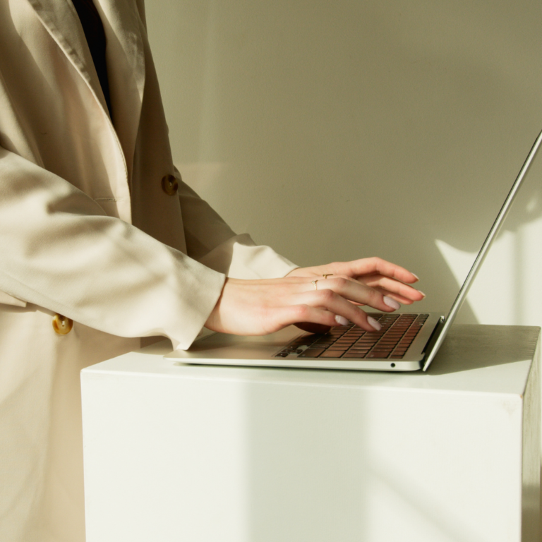 Person in Beige Coat Typing on Her Laptop