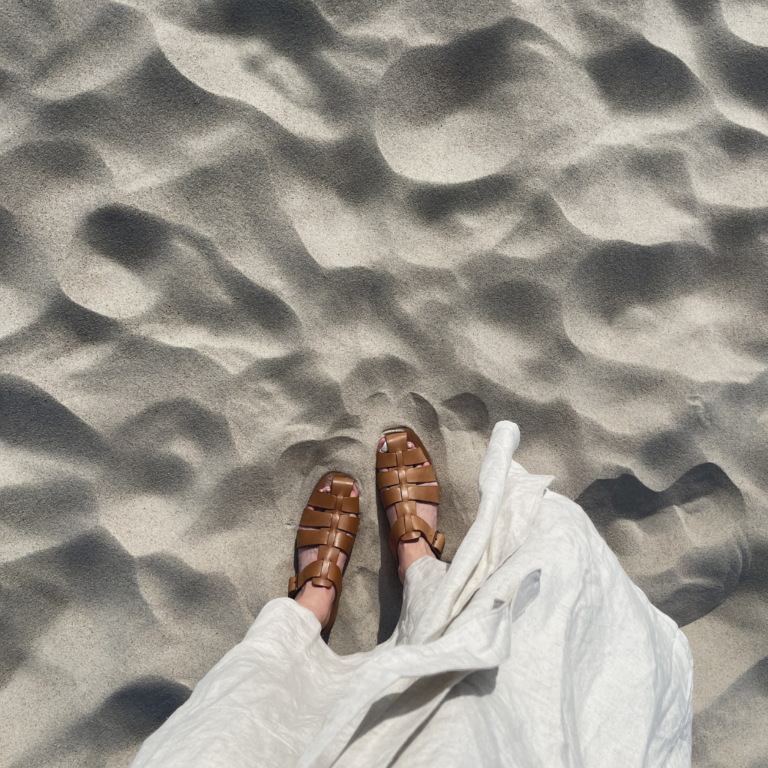 Woman's Feet Wearing Sandals on Sand