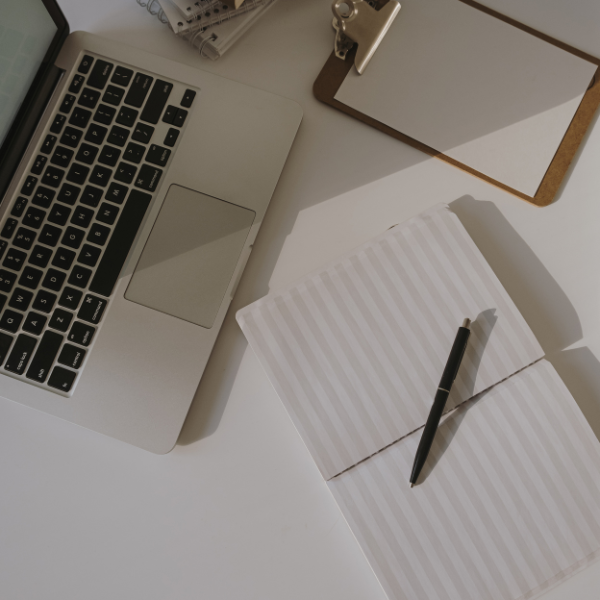 laptop, notebook, and pen on a white table